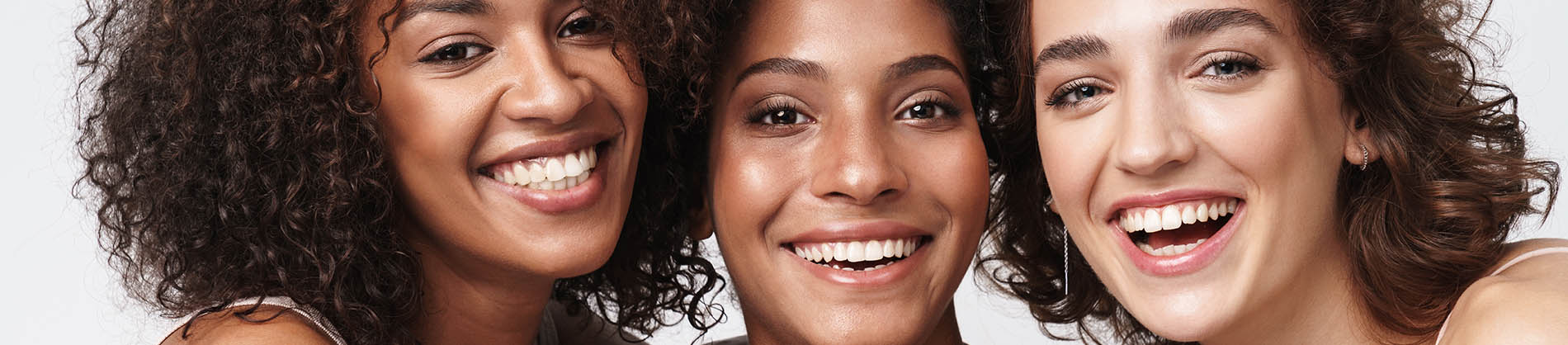 The image is a photograph of a woman with light skin, smiling at the camera. She appears to be in her late twenties or early thirties and has long hair. Her eyes are looking directly at the camera, and she is holding up her index finger near her mouth as if she s making a point or emphasizing something. The background is plain and light-colored, which suggests that this could be a stock photo used for various purposes such as advertising, personal branding, or lifestyle content.